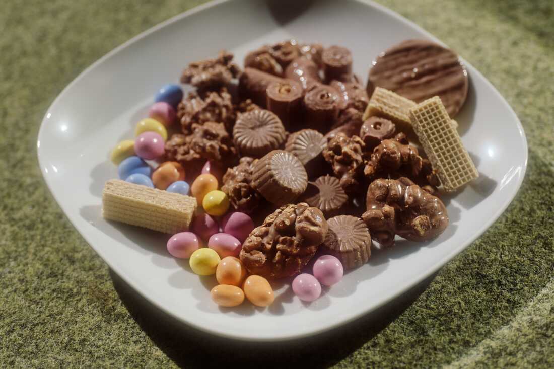 This photo shows a white plate full of various ChoViva treats. Some of them are brown candies. Others are shaped like small eggs and have pastel colored coverings. Some of them are ChoViva clusters and nuts.